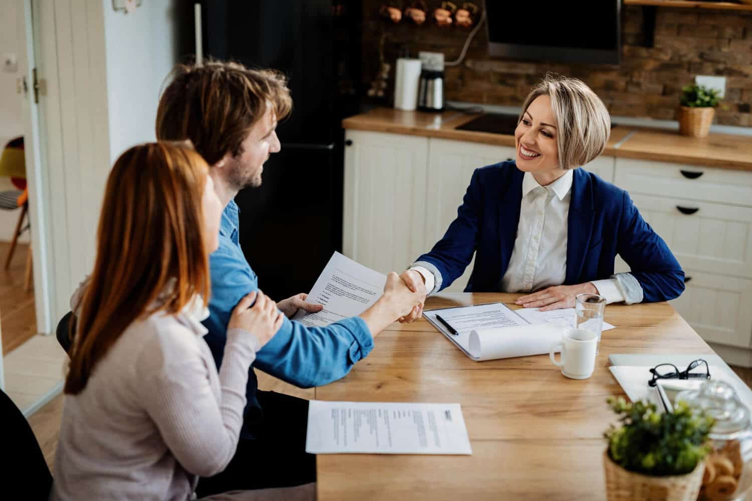 A couple successfully applying for their mortgage with AFB, shaking hands with a certified AFB mortgage broker, celebrating a successful loan application.