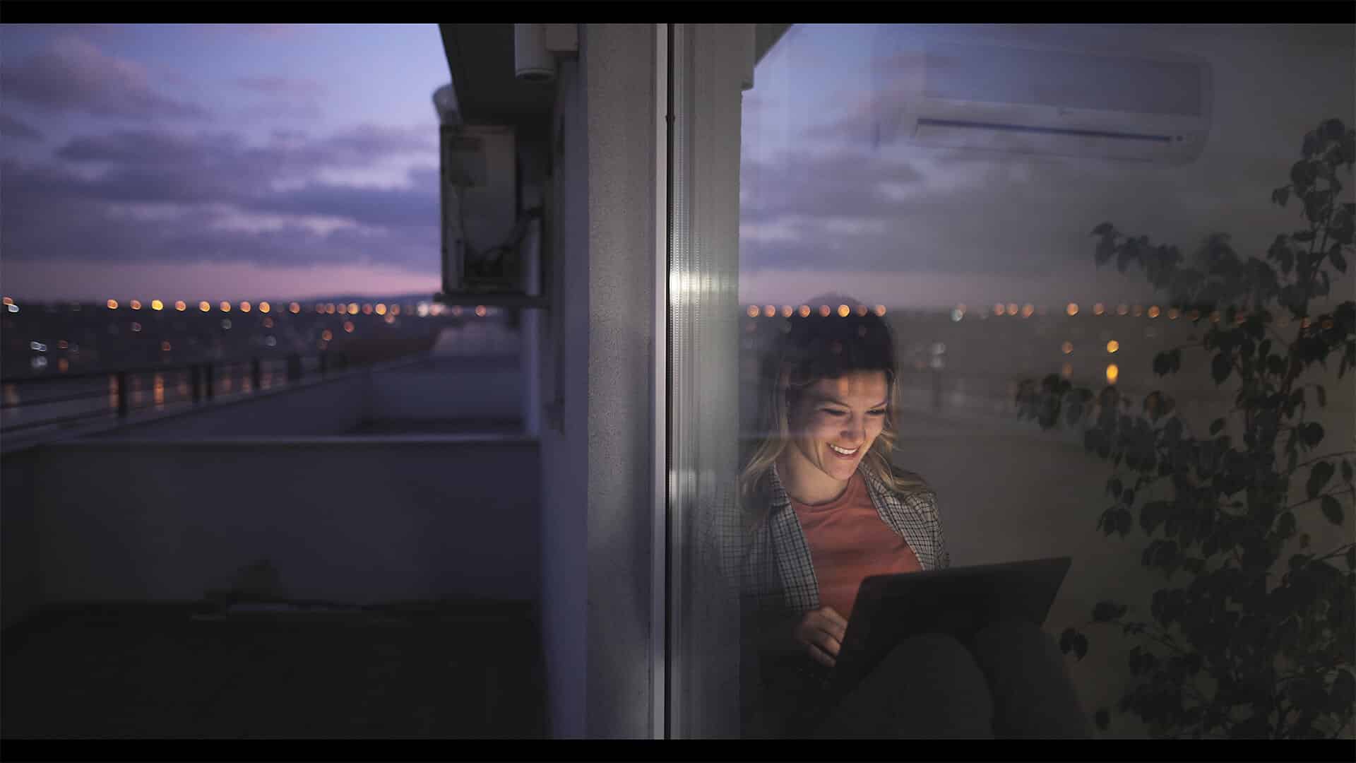 A woman in an apartment smiling while applying for a loan with AFB online, happy with the simple and easy process.