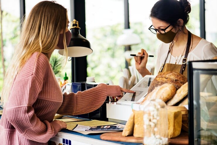 A customer ordering food and drink at a cafe counter.