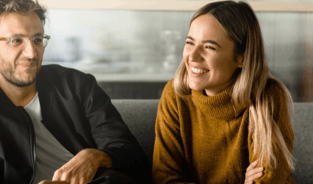 Two people smiling during a relaxed financial consultation at Apex Finance Brokers.